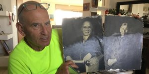 Ein Mann zeigt alte Fotos von einem Mann und einer Frau