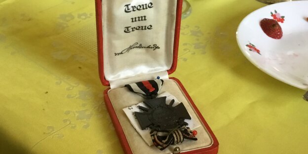 Ein Eisernes kreuz in einem Etui auf gelber Tischdecke Ein Eisernes kreuz in einem Etui auf gelber Tischdecke