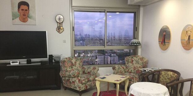 Ein Wohnzimmer mit Sesseln einem Fernseher und darüber hängt das Bild eines jungen Mannes Ein Wohnzimmer mit Sesseln einem Fernseher und darüber hängt das Bild eines jungen Mannes