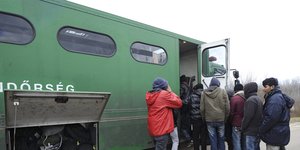 Geflüchtete steigen in einen Bus der ungarischen Polizei ein