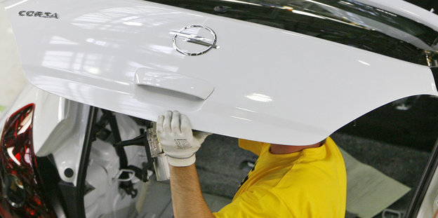 Ein Arbeiter trägt ein Teil eines Opel Corsa auf dem Kopf