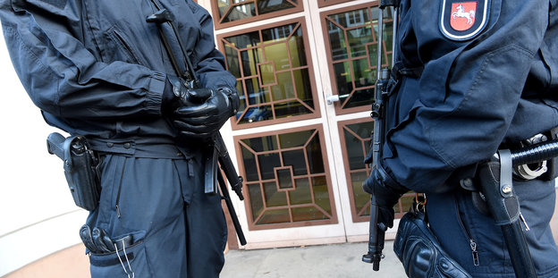 Zwei Polizisten stehen mit Waffen in der Hand vor einer Tür
