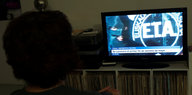 Eine Frau schaut auf einen Fernseher, in dem das Symbol der ETA zu sehen ist.