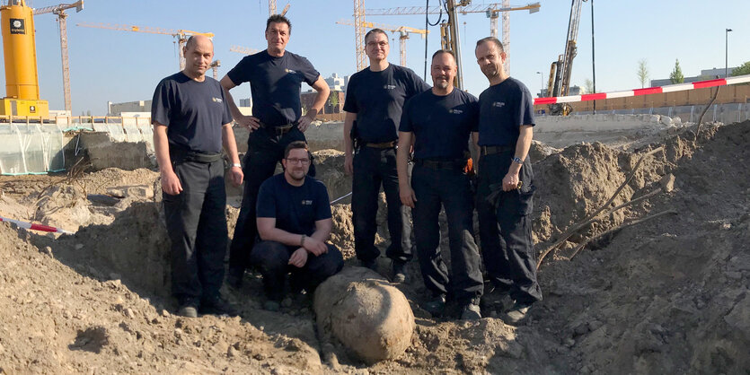 Sechs Mitarbeiter der Feuerwehr stehen auf und neben der Weltkriegsbombe