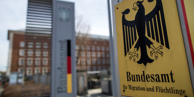 Ein Gebäude und davor ein Schild mit dem Bundesadler und der Aufschrift Bundesamt für Migration und Flüchtlinge