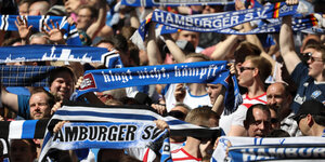HSV-Fans im Stadion halten ihre Schale hoch.