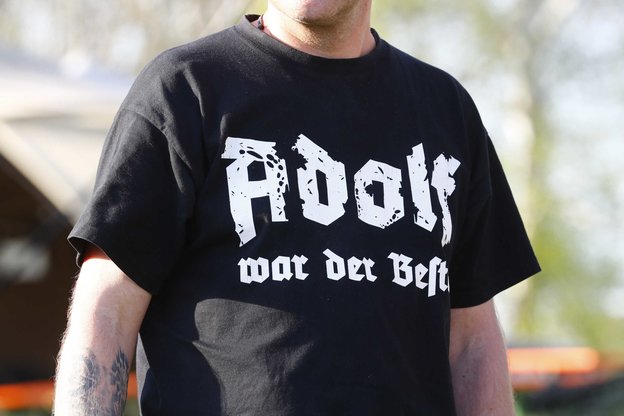 Ein Mann mit schwarzem T-Shirt mit der Aufschrift "Adolf war der Beste"