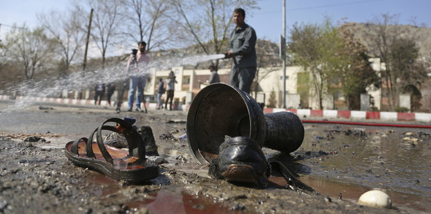 Schuhe, Sandalen und ein Becher liegen auf einer Straße in Kabul