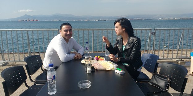 Ein Mann und eine Frau bei einem Snack an einem Tisch am Meer