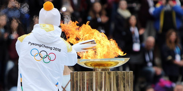Sportler entzündet olympisches Feuer