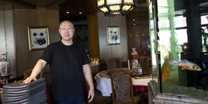 Der Besitzer eines chinesischen Restaurants posiert vor einem Aquarium