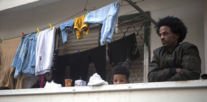 Ein Mann mit Kind auf einem Balkon, auf dem auch Wäsche hängt