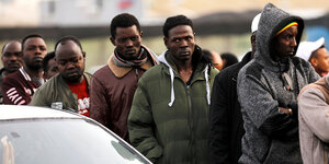 Afrikanische Migranten warten in einer Schlange neben einem Auto vor israelischen Behörden