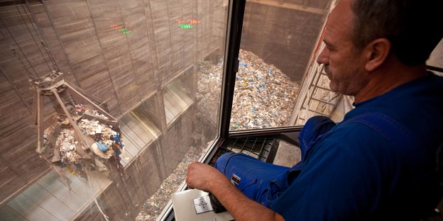 Ein Arbeiter schaut in einen Müllbunker
