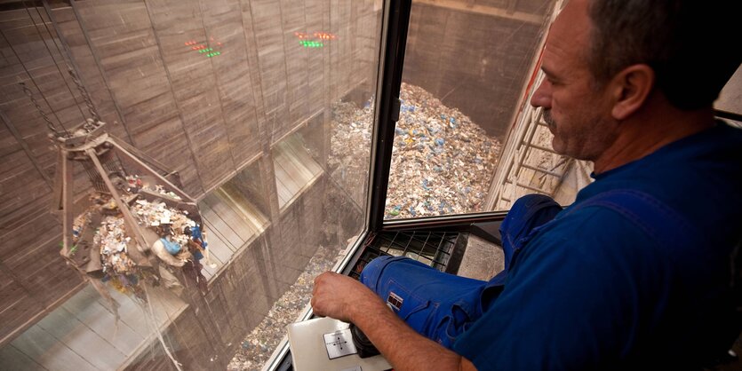 Ein Arbeiter schaut in einen Müllbunker