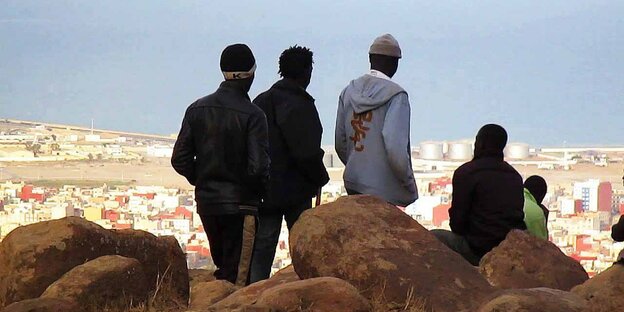Fünf Personen blicken von einem Hügel auf die Stadt Melilla.