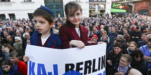 Ein Junge und ein Mädchen halten ein Plakat "Berlin trägt Kippa", im Hintergrund weitere Demonstranten
