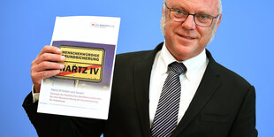 Ulrich Schneider zeigt Broschüre zu Hartz