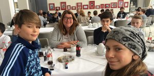 Bremens Sozialsenatorin Anja Stahmann sitzt mit Schülern an einem Tisch.