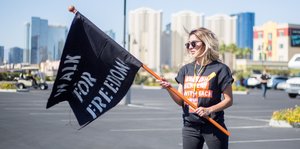 Eine Frau hält eine schwarze Flagge auf der Freedom steht