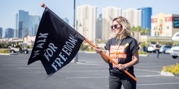 Eine Frau hält eine schwarze Flagge auf der Freedom steht