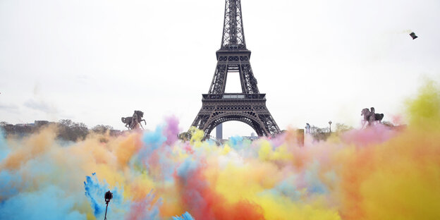 Menschen bewerfen sich vor dem Eiffelturm in Paris mit bunten Farben