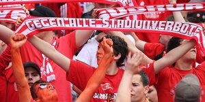 Menschen in roter Kleidung. Einer hält einen Schal mit der Aufschrift „Gegen alle Stadionverbote"