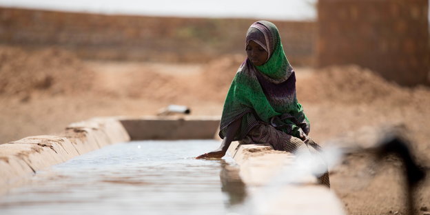 Frau sitzt am Rand eines Wasserbeckens in Äthiopien