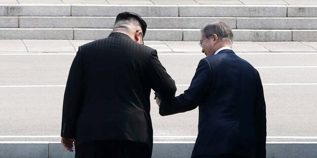 Kim Jong Un, Machthaber von Nordkorea, und Moon Jae In, Präsident von Südkorea, gehen Hand in Hand über die Betonschwelle, die die Grenze zwischen ihren Ländern markiert, nach Nordkorea