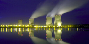 Ein Atomkraftwerk am Wasser, aus dessen Türmen Rauch aufsteigt