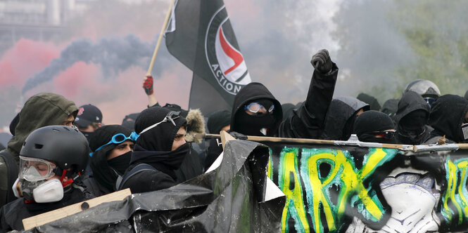 Vermummte Demonstrierende mit Antifa-Fahne