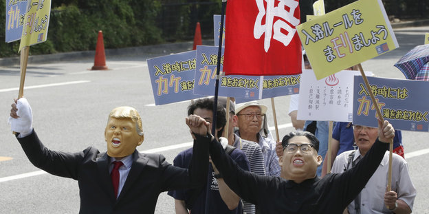 Demonstrant*innen in Tokyo tragen Masken von Donald Trump und Kim Jong Un