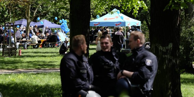 Polizisten in einem Park, im Hintergrund kleine Festpavillons