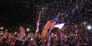 Menschen halten armenische Flaggen und es regnet Konfetti