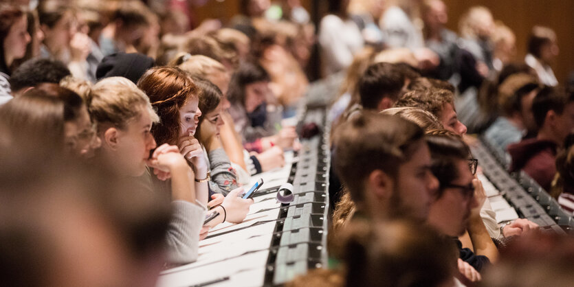 Studierende sitzen in den Bänken eines Hörsaals