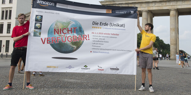 Zwei Aktivisten halten Schild mit Aufschrift "Erde nicht verfügbar" vorm Brandenburger Tor hoch