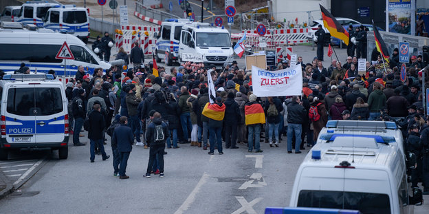 Demonstranten mit Deutschlandfahnen, Plakaten und Polizeischutz.