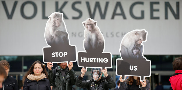 Aktivisten halten Schilder mit Affen vor VW-Logo in die Höhe
