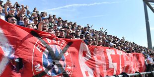 Löwenfans mit einem Schmähtransparent gegen den FC Bayern