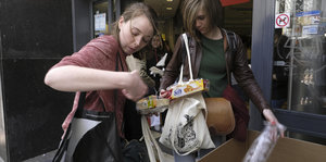 Zwei Einkäuferinnen entsorgen überflüssiges Plastik vor einem Brüssler Supermarkt