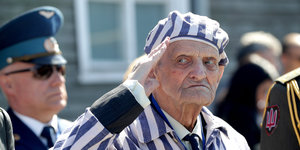 ein alter Mann in KZ-Uniform salutiert