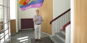 Der Friedensaktivist Reiner Braun hält eine Regenbogenfahne mit "Peace" in der Hand