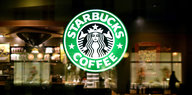 Eine Reklametafel mit dem Logo der Cafehauskette Starbucks Coffee leuchtet an einer Filiale des Unternehmens.