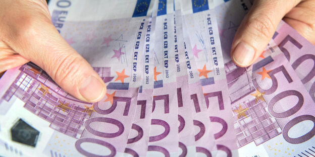 Zwei Hände halten viele 500-Euro-Geldscheine