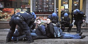 Demonstranten sitzen auf dem Boden als sie von Polizisten festgenommen werden