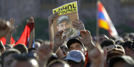 eine Menschenmenge, ein Mann hält ein Plakat mit einem Bild des Oppositionspolitikers Paschinjan in die Höhe