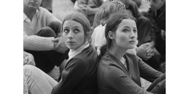 Zwei junge Frauen sitzen bei einem Protest auf dem Boden Zwei junge Frauen sitzen bei einem Protest auf dem Boden