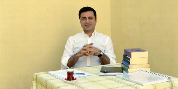 Selahattin Demirtaş sitzt an einem Tisch, auf dem ein Stapel Bücher liegt und eine Tasse Tee steht