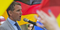 Björn Höcke schreit vor Deutschlandfahne in ein Mikrofon
