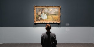 Eine Frau sitzt vor einem Bild von Thomas Gainsborough.